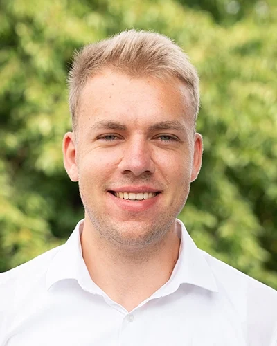 Porträt eines lächelnden Mannes vor grünem Hintergrund